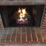 Hargrove radiant heat Cross Timber gas logs inside wood burning fireplace.