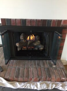 Recently installed natural gas log set into wood burning fireplace.